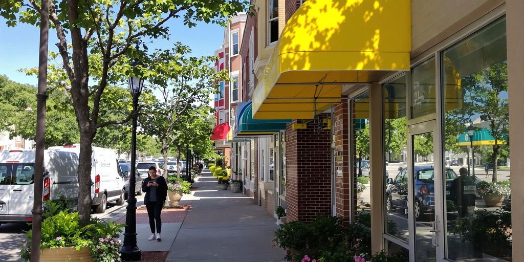Colorful storefront awnings, delivery van, pedestrian with smartphone on sidewalk